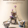 A set of decorative candles in ornate tins and glass holders with floral designs on a light surface.
