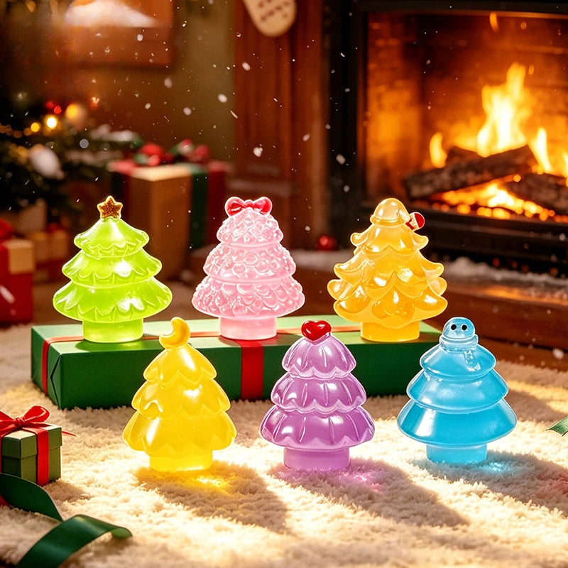 A collection of colorful resin Christmas tree charms in green, pink, yellow, and blue resting on a white fuzzy surface.