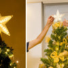 Hands place an LED glowing star topper on a decorated Christmas tree.