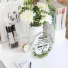 A clear acrylic keepsake with an inspirational message is displayed next to a bouquet of white flowers and a stack of books.