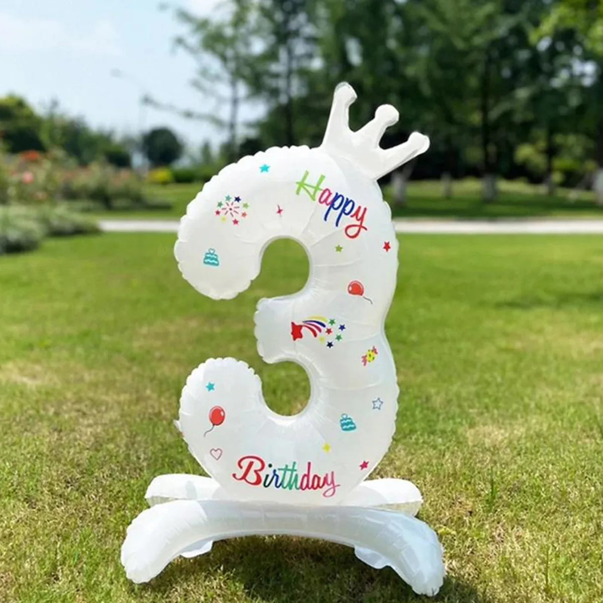 A white foil balloon shaped like the number 3 with a crown and birthday confetti design standing on a base.