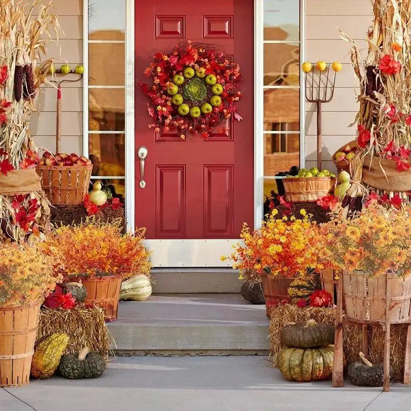 A vibrant artificial fall flower bouquet featuring red and orange foliage displayed near a red door.