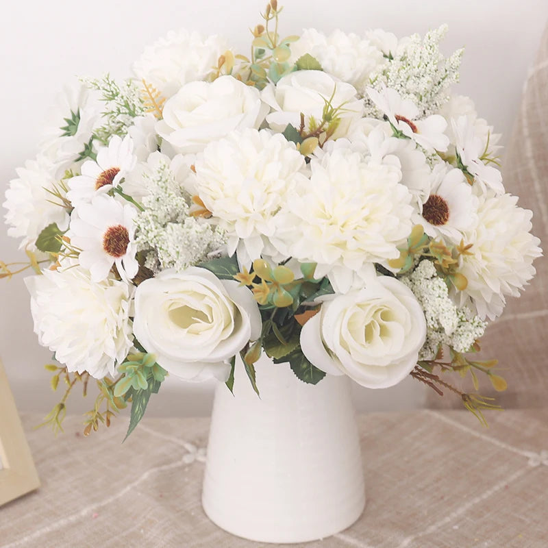 A white floral bouquet featuring roses, hydrangeas, and delicate greenery arranged in a white vase.