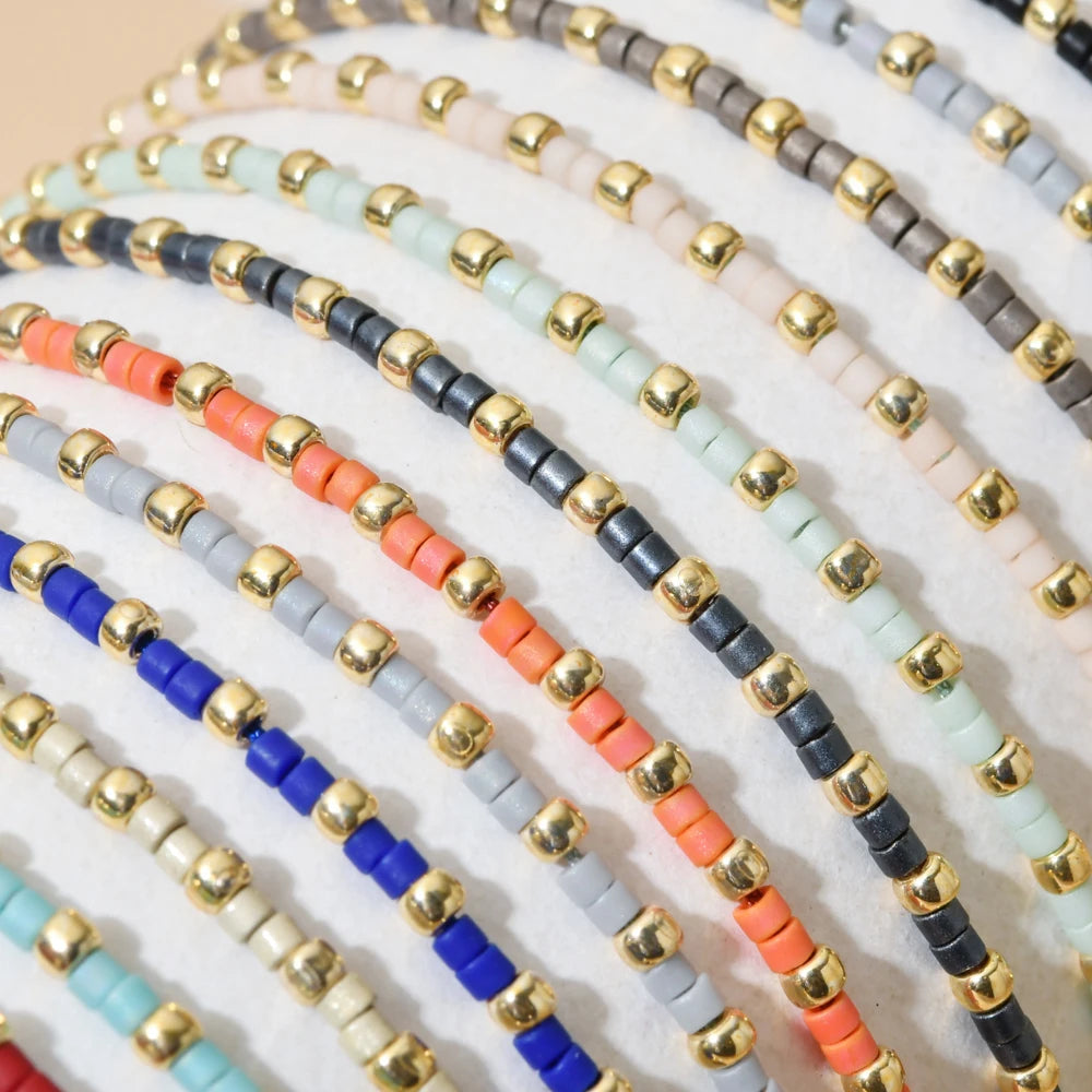 Handmade boho glass bead bracelet with adjustable cord featuring various colors like black, gold, blue, and orange.