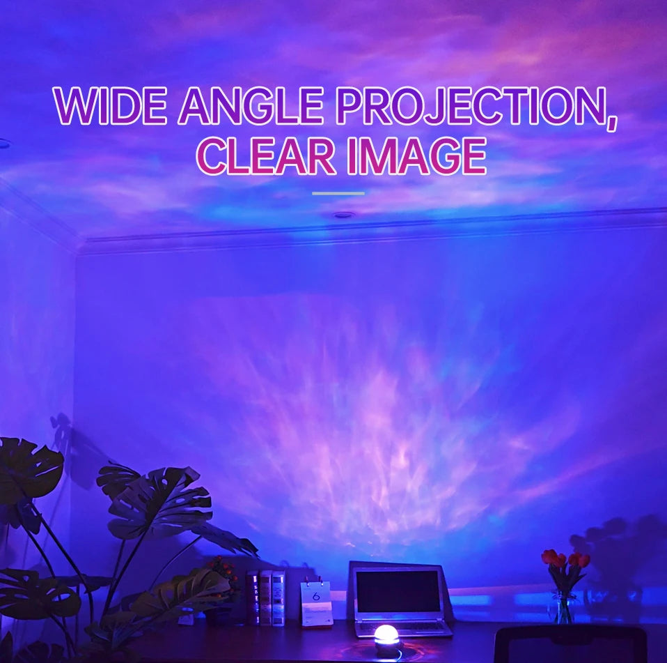 A wide angle projection night light displays colorful light patterns on a wall with tropical plants and a laptop.