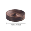 A round, dark brown solid wood incense stick burner with a small opening at the top.