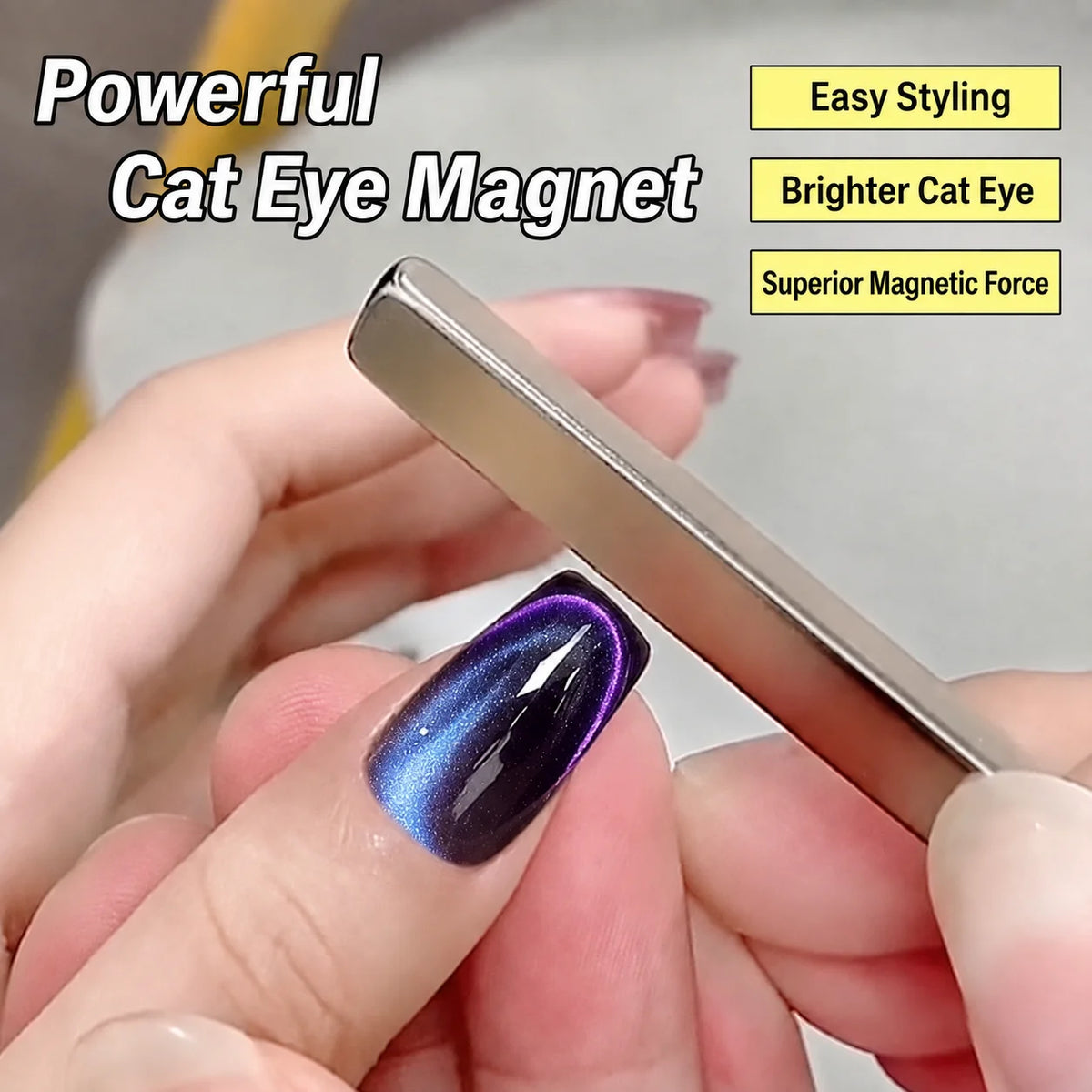 A hand holds a silver rectangle cat eye magnet with a purple iridescent gel polish on a fingernail.