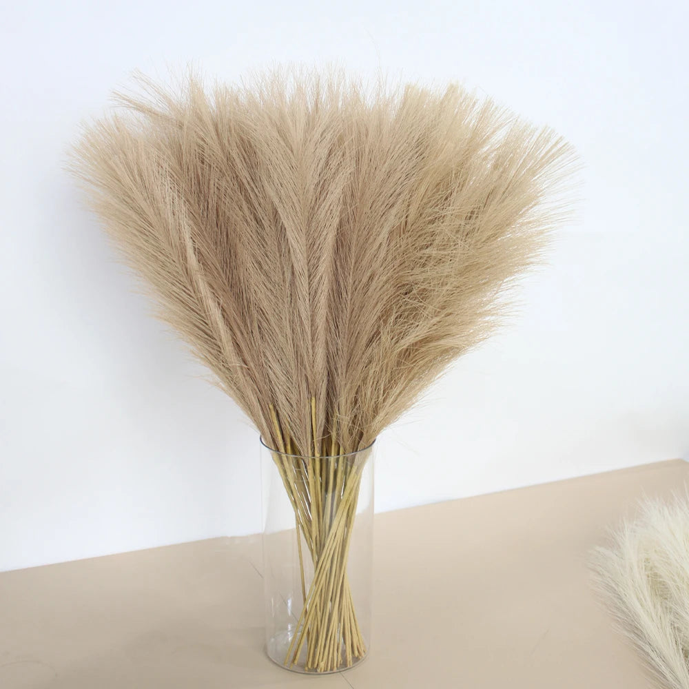 A bouquet of dried beige pampas grass arranged in a clear glass vase.