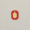 A small, gold-colored figurine of a tortoise is set against a red background.
