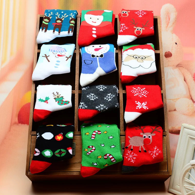 A wooden tray displaying a five-pack of Christmas women's socks featuring reindeer, tree, and festive patterns in red, green,