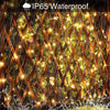 Close-up of warm yellow fairy string lights illuminating a dense hedge or fence with a diamond pattern.