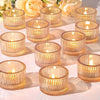 A collection of gold glass tealight candle holders arranged on a white surface.