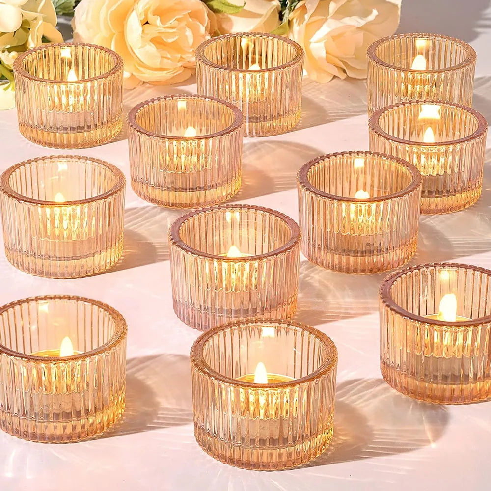 A collection of gold glass tealight candle holders arranged on a white surface.