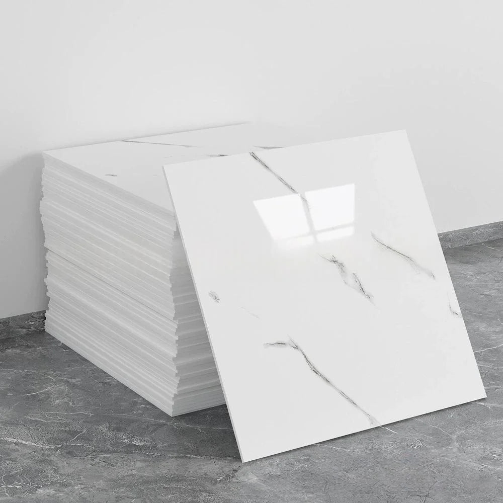 A rectangular white marble tile sticker is displayed next to a stack of similar tiles on a gray floor.