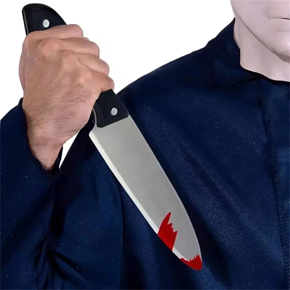 A hand holds a silver knife with a red blade detail against a dark blue fabric.