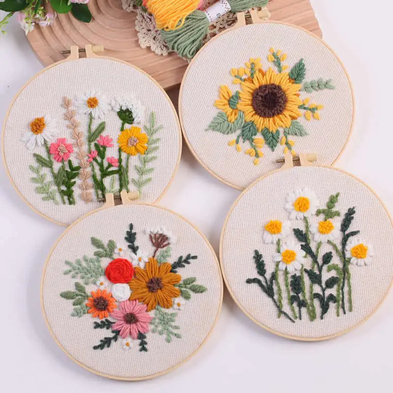 Punch needle embroidery kit featuring stamped cloth and tools with floral designs of sunflowers and daisies