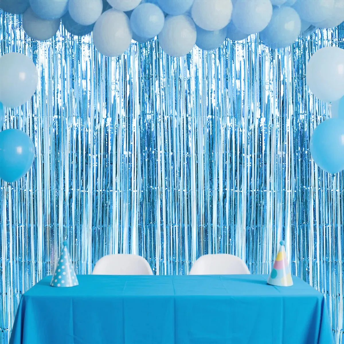 A bright blue sequin glitter party backdrop featuring hanging blue balloons and a table setup.