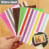 A hand holds a stack of colorful PVC photo corner protectors for scrapbooking and albums.