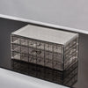 Clear acrylic jewelry organizer with three drawers shown on a reflective surface.