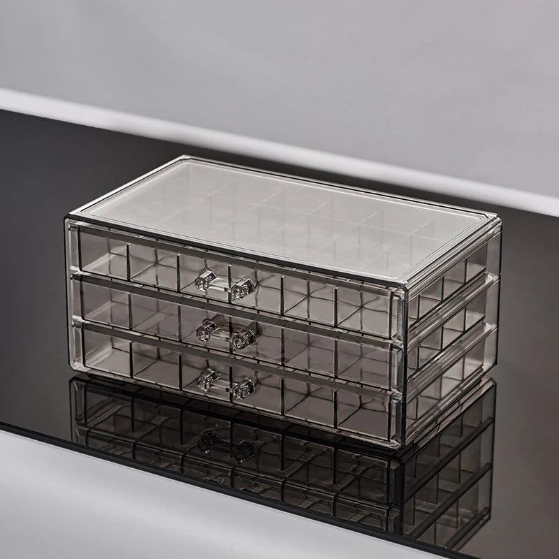 Clear acrylic jewelry organizer with three drawers shown on a reflective surface.