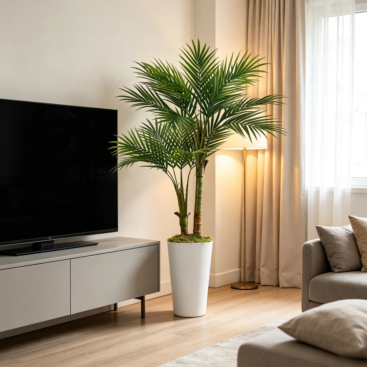 A tall artificial areca palm tree in a white planter decorates a living room beside a television.
