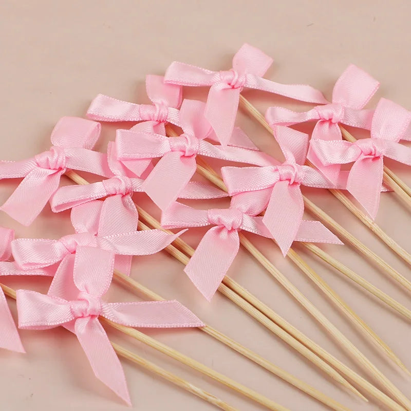 Pink bow cupcake toppers on wooden sticks for parties and celebrations