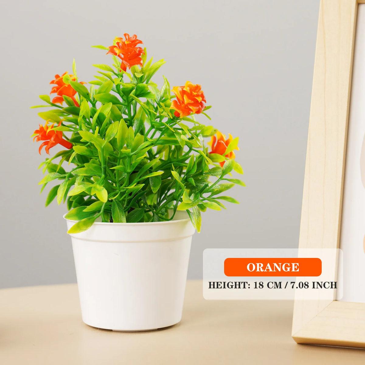 A potted artificial bonsai tree with bright orange flowers and green leaves on a light background.