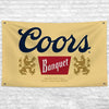 A beige banner featuring the Coors Banquet beer logo in dark blue and red, with text indicating it is brewed with Rocky Mount