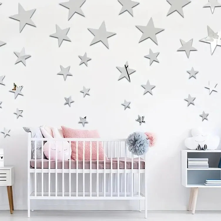 A white crib decorated with pink and gray stars, set against a white wall backdrop.