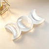A white natural selenite triple moon charging bowl resting on a light beige surface.