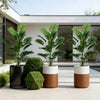 Three potted artificial palm trees with green leaves displayed on a light-colored patio surface.