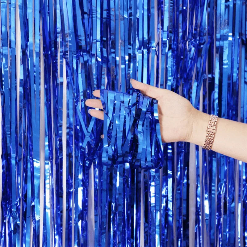 A hand is pulling down blue metallic foil fringe curtain streamers.