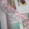 Close-up of delicate pink and gray lace trim with a bow detail used as an embroidery accent.