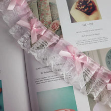 Close-up of delicate pink and gray lace trim with a bow detail used as an embroidery accent.