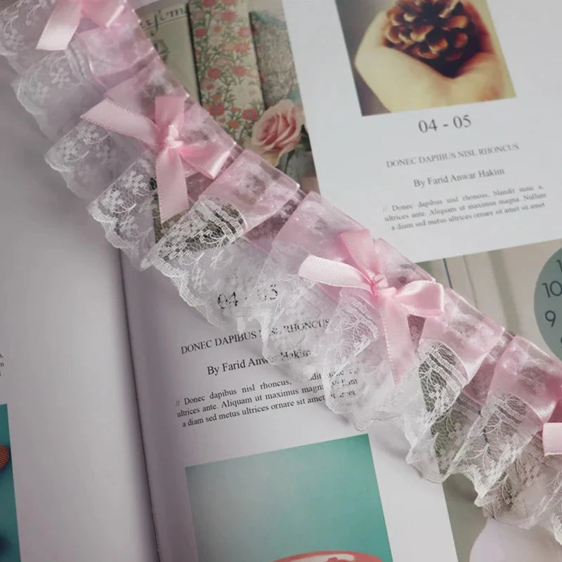 Close-up of delicate pink and gray lace trim with a bow detail used as an embroidery accent.