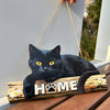 A black cat silhouette rests on a rustic wooden sign with the word HOME carved into it.