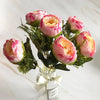 A bouquet of pink and peach silk rose and peony artificial flowers displayed in a glass jar.