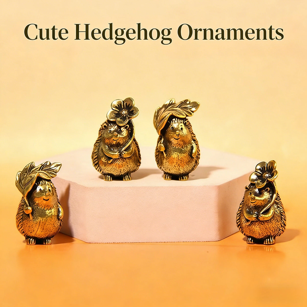 Two brass hedgehog ornaments with textured bodies and leafy tufts displayed on a light pink pedestal.