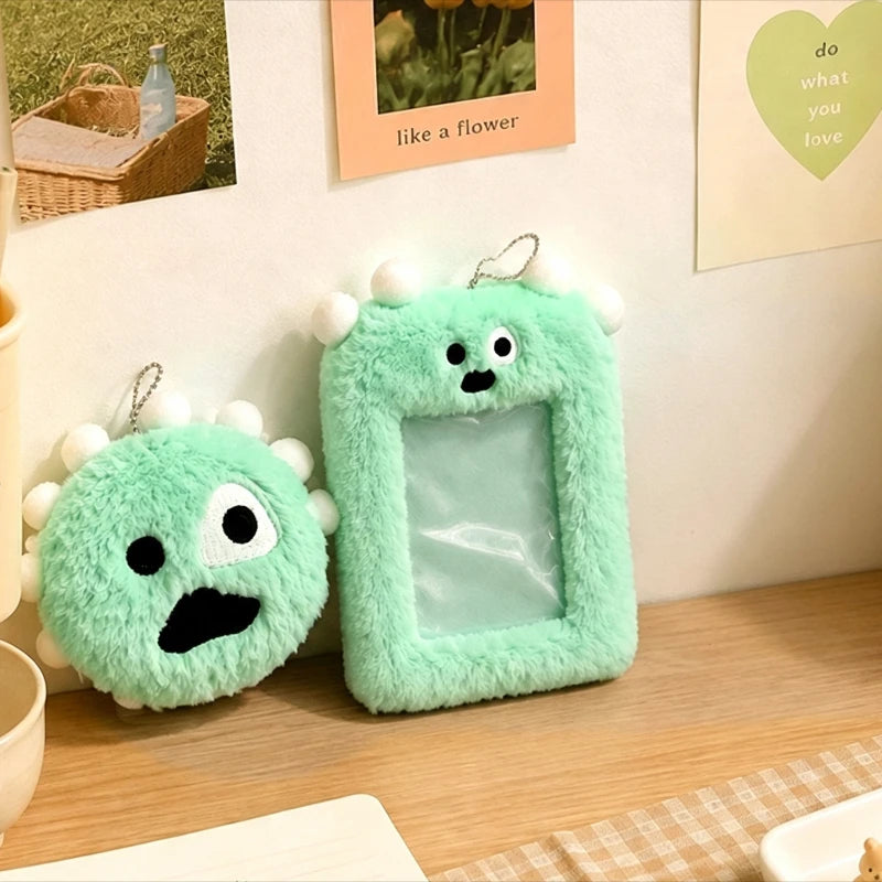 A pair of green fuzzy plush keychains with clear photo holders displayed on a wooden surface.