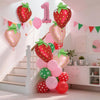 A display of red and pink strawberry foil balloons decorating a staircase with festive bunting.