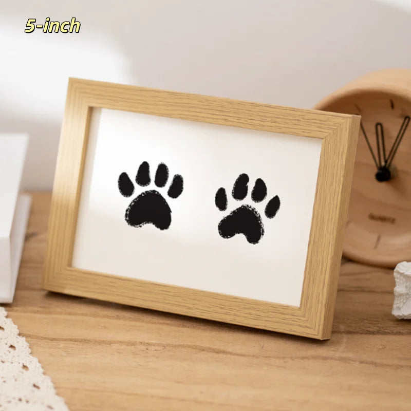 A wooden photo frame displaying two black paw prints on a white background.