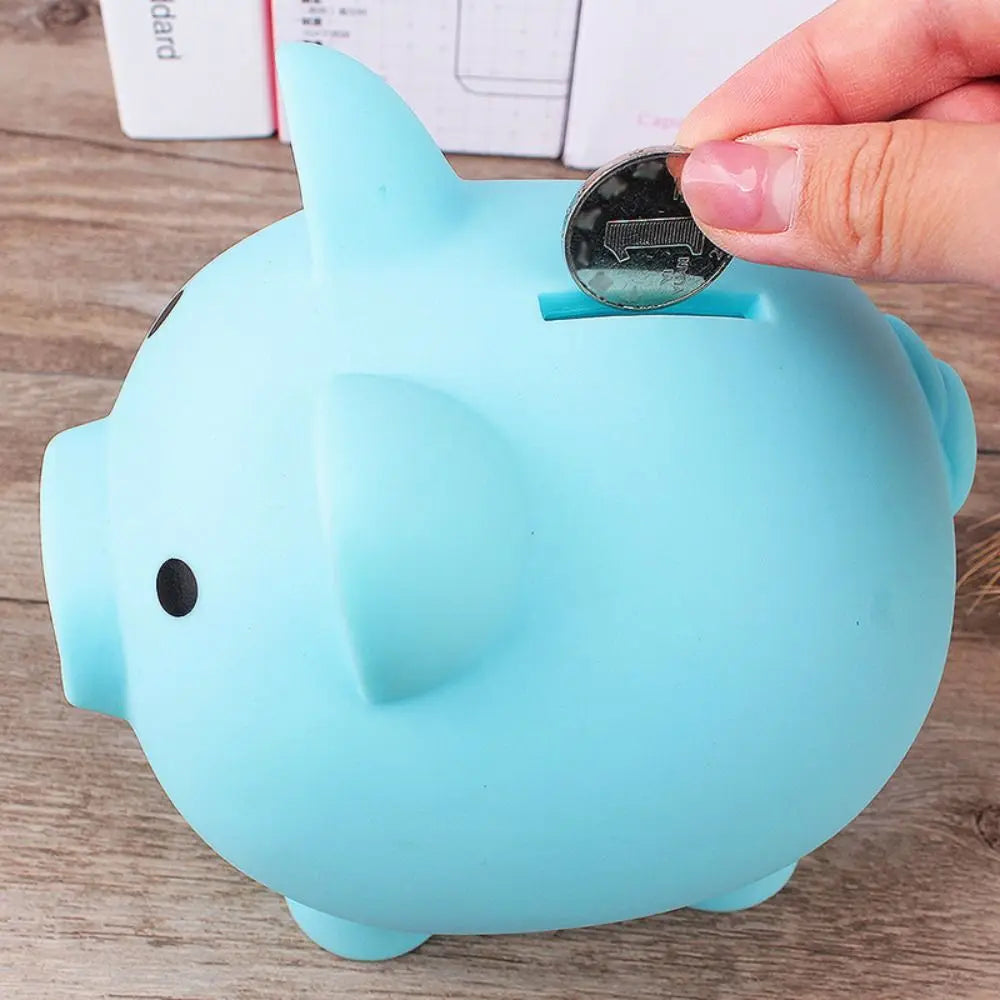 A light blue pig-shaped coin storage bank with a tray is being opened by a hand.