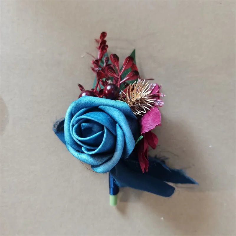A boutonniere set featuring a dusty blue silk rose and various dried floral accents.