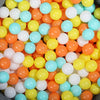 A pile of colorful, round plastic balls in shades of orange, yellow, and light blue.