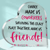 A clear heart-shaped plaque engraved with text celebrating coworkers surviving a crazy place together and making them friends