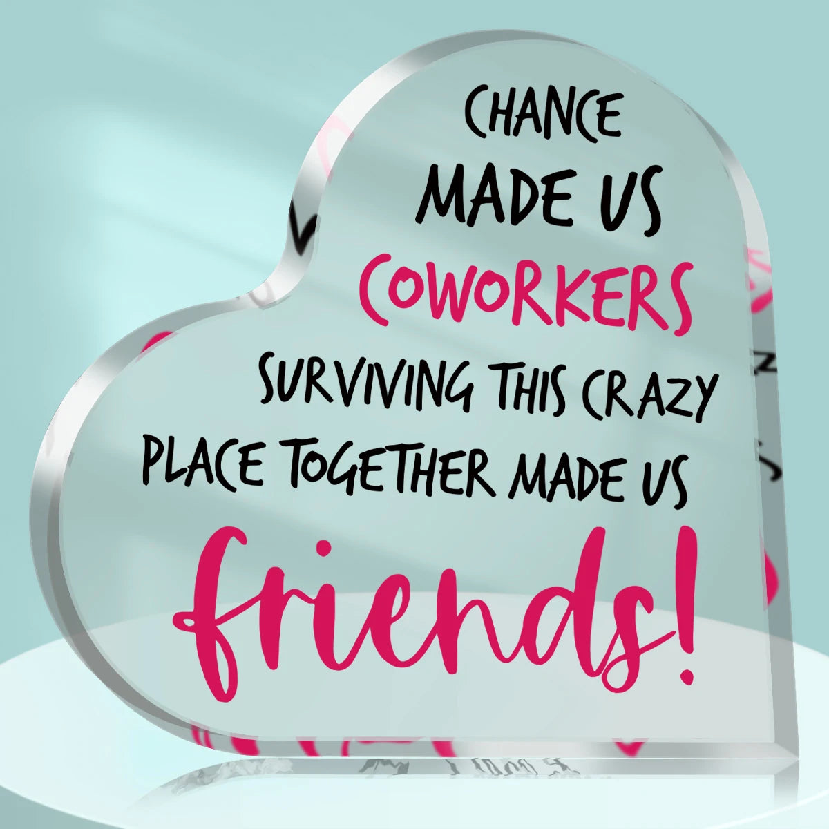 A clear heart-shaped plaque engraved with text celebrating coworkers surviving a crazy place together and making them friends