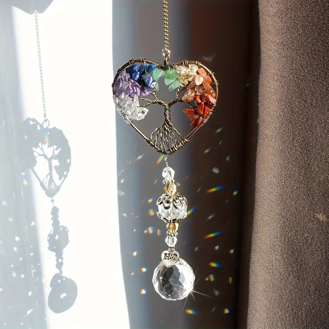 A hanging rainbow crystal tree of life sun catcher with colorful crystals and a clear pendant.