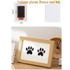 A wooden photo frame displaying black paw prints on white paper, ready for use with ink.