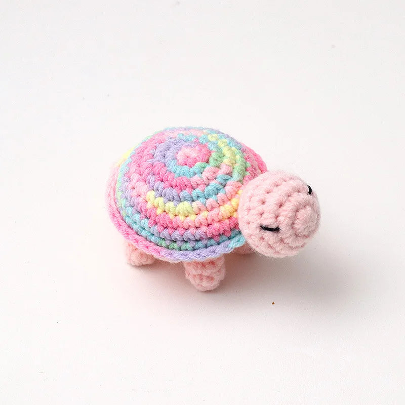 Handmade crocheted turtle plush toy in pink and blue colors.