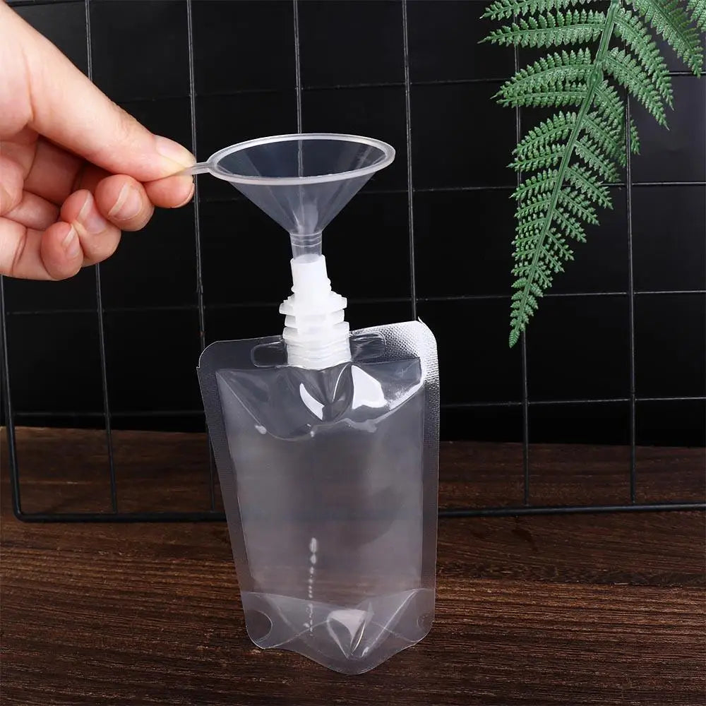 A hand is squeezing a clear reusable liquid drink pouch, demonstrating its squeezable feature.